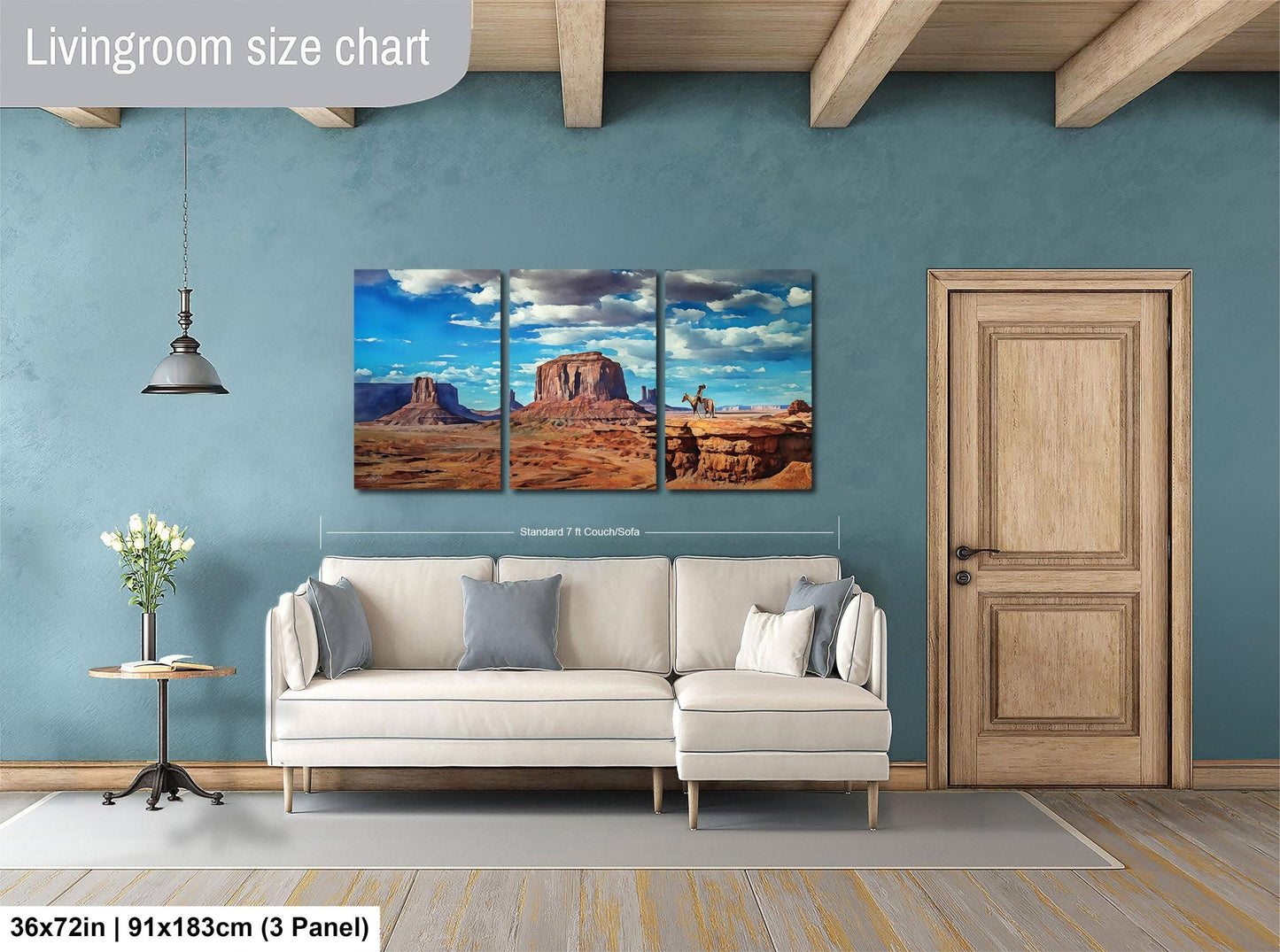 The image is a living room with a large wall art depicting a desert landscape with mountains and a blue sky. The living room has a white sofa and a wooden door.