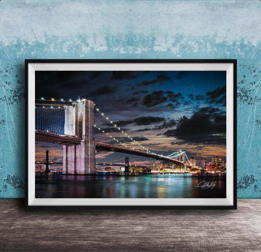 A framed photograph of the Brooklyn Bridge at night, with its iconic towers and suspension cables illuminated against a dark sky.