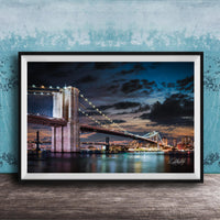 A framed photograph of the Brooklyn Bridge at night, with its iconic towers and suspension cables illuminated against a dark sky.