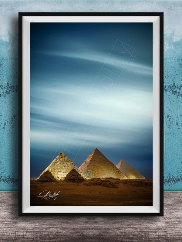 A framed photograph of the iconic pyramids of Giza in Egypt, with the sky and clouds in the background.