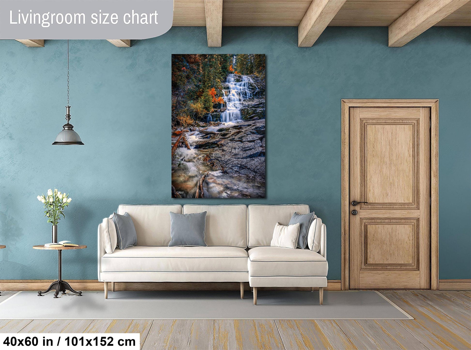 a living room with a large white sofa, a wooden door, and a painting of a waterfall hanging on the wall.