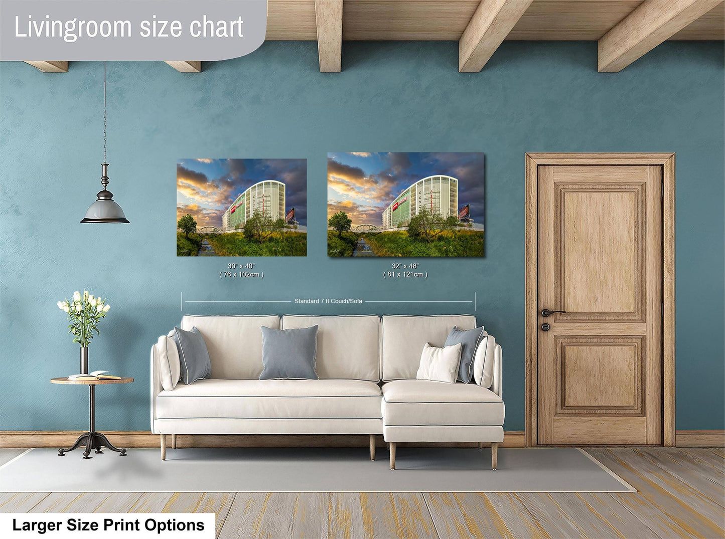 a living room with a white sofa and a wooden door. Above the sofa, there are two framed pictures of a building, likely a hotel, with different sizes and dimensions. The room has a blue wall and a wooden ceiling, creating a cozy and inviting atmosphere.