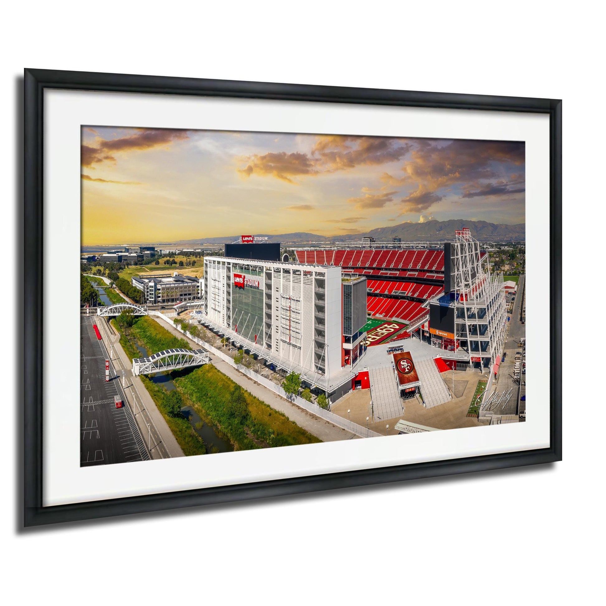 The image is a framed picture of a large stadium with a red roof, surrounded by a cityscape with buildings and a bridge.