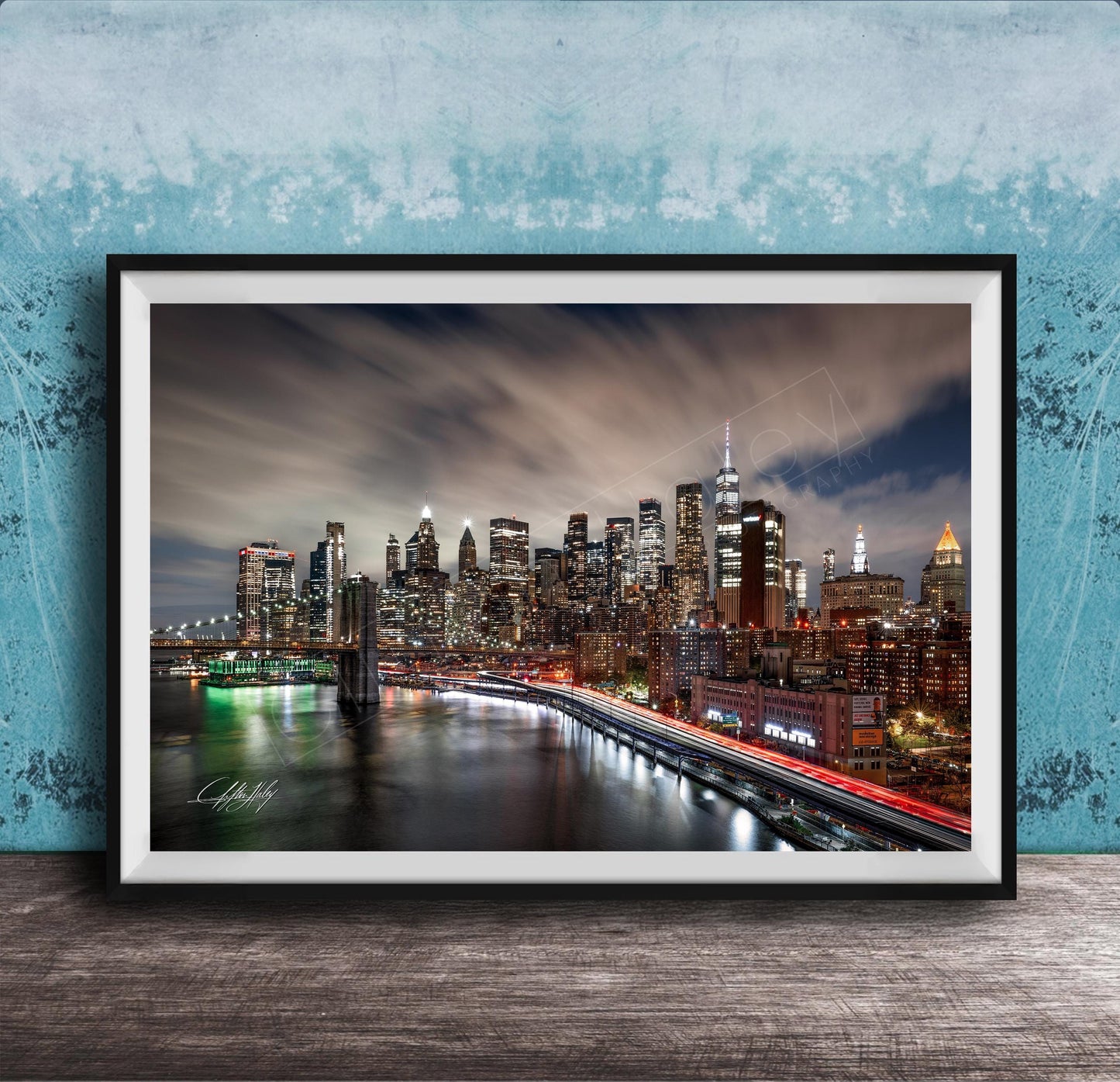 A framed photograph of the New York City skyline at night, with the city's iconic landmarks and buildings illuminated against a dark sky.