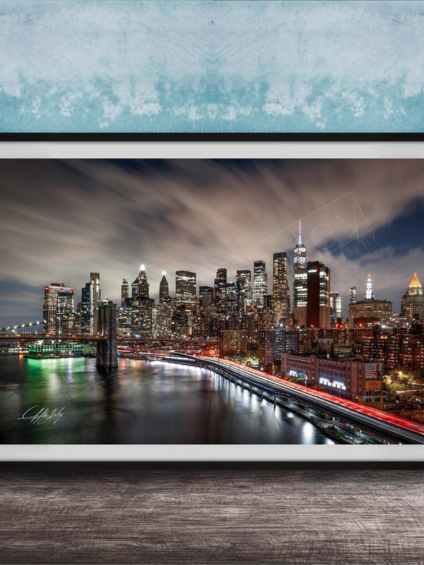 A framed photograph of the New York City skyline at night, with the city's iconic landmarks and buildings illuminated against a dark sky.
