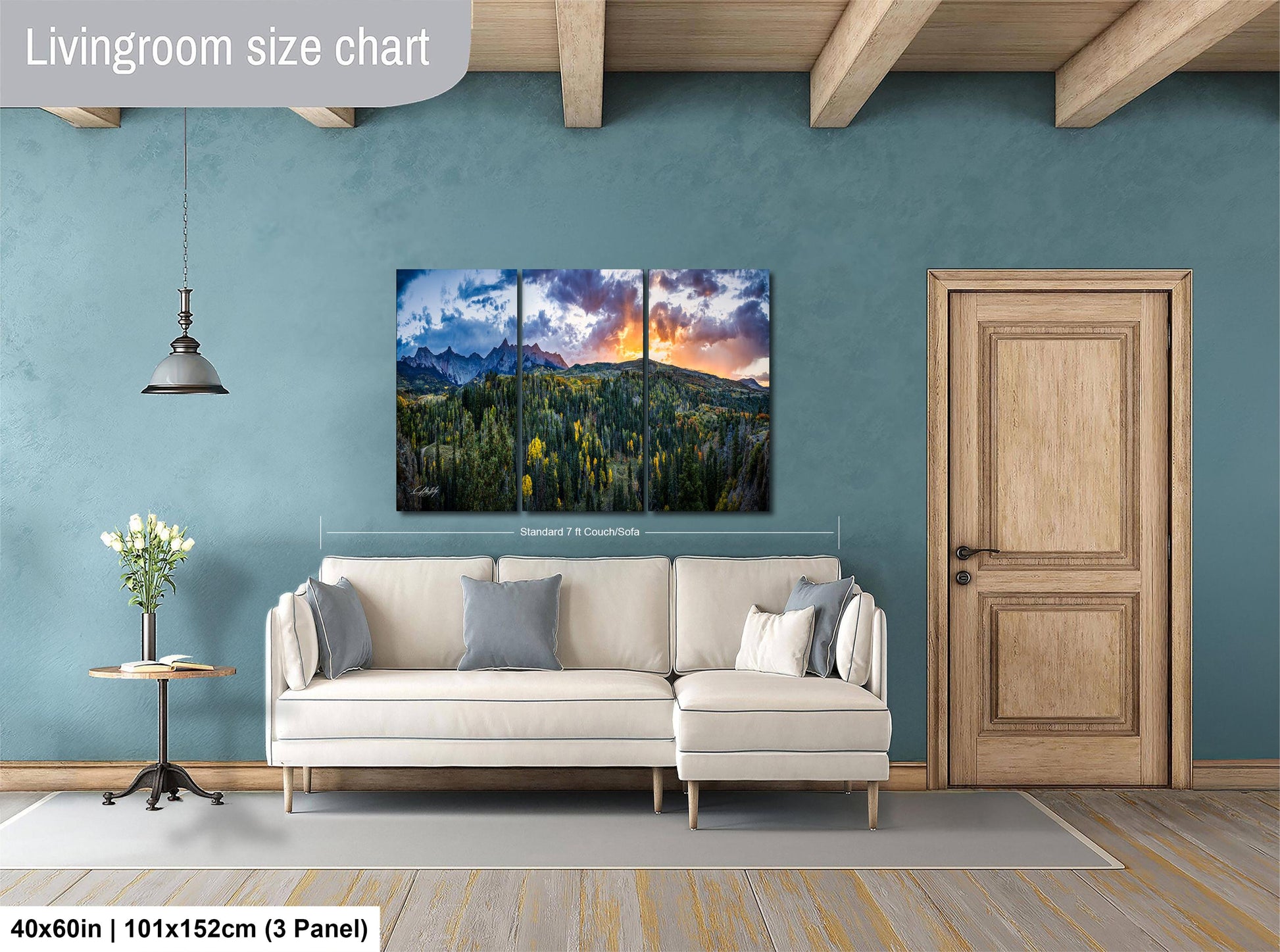 a living room with a large, colorful landscape painting hanging on the wall. The painting depicts a mountain range with a sunset sky. The living room has a white sofa and a wooden door. The painting is approximately 40 inches wide and 101 inches tall, and it is mounted on a wooden panel.