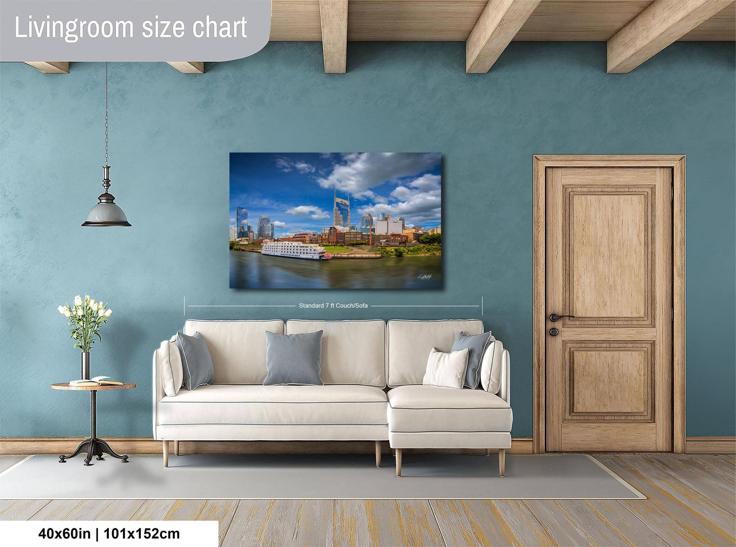 a living room with a large white sofa, a wooden door, and a painting of a cityscape hanging on the wall.