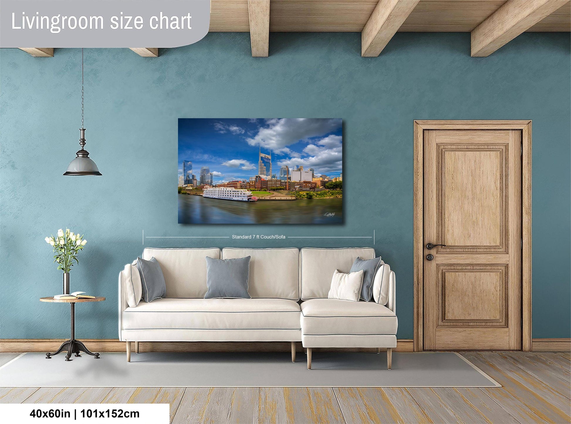 a living room with a large white sofa, a wooden door, and a painting of a cityscape hanging on the wall.