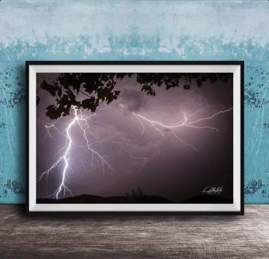 A framed photograph of a dramatic lightning storm with bolts of light illuminating the dark sky.