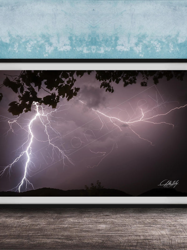 A framed photograph of a dramatic lightning storm with bolts of light illuminating the dark sky.