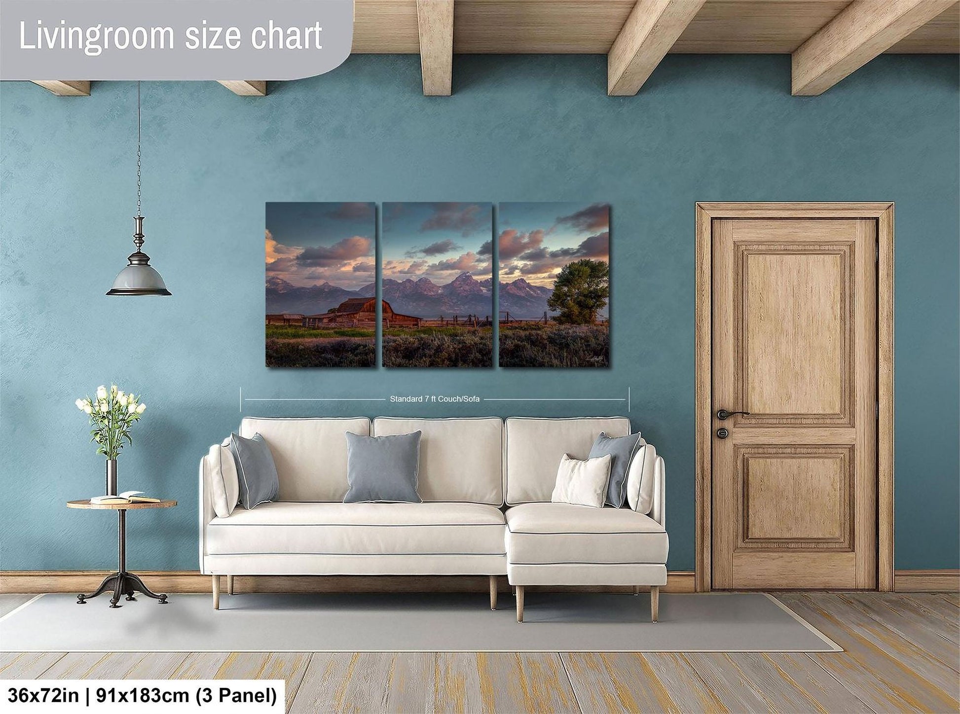 The image is a living room with a large, three-panel landscape painting hanging on the wall. The painting depicts a serene mountain scene with a sunset. The room has a white sofa and a wooden door, creating a cozy and inviting atmosphere.