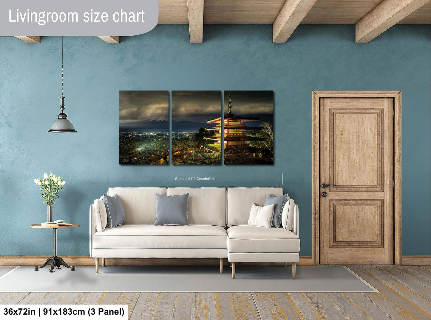 The image is a living room with a large, three-piece wall art depicting a city skyline at night. The wall art is mounted above a white sofa, and there is a wooden door and a small table with a vase of flowers nearby. The living room has a blue wall and wooden flooring, creating a cozy and inviting atmosphere.