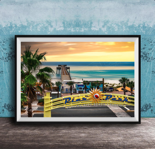 A framed photograph of a tropical beach scene with palm trees, a pier, and a sunset over the ocean.