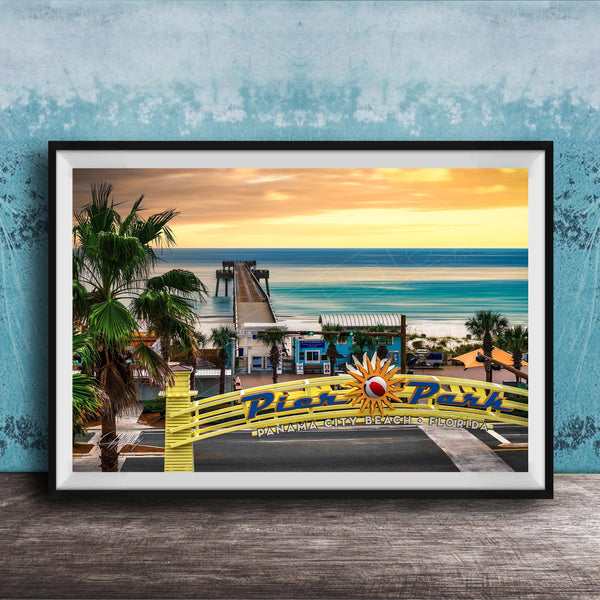 A framed photograph of a tropical beach scene with palm trees, a pier, and a sunset over the ocean.