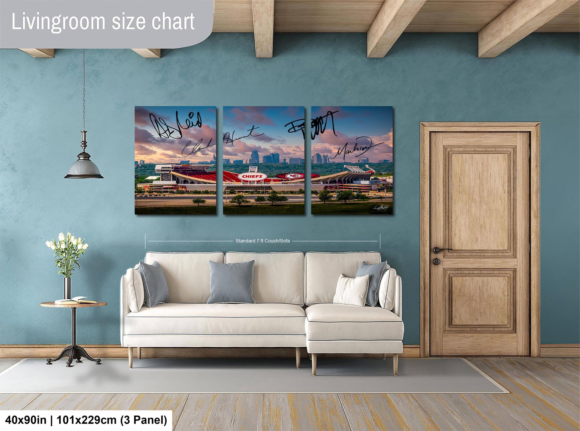 The image is a living room with a white sofa and a wooden door. Above the sofa, there is a large living room size chart that provides dimensions for the artwork. The artwork is a collage of three pictures depicting a cityscape with a stadium in the background.