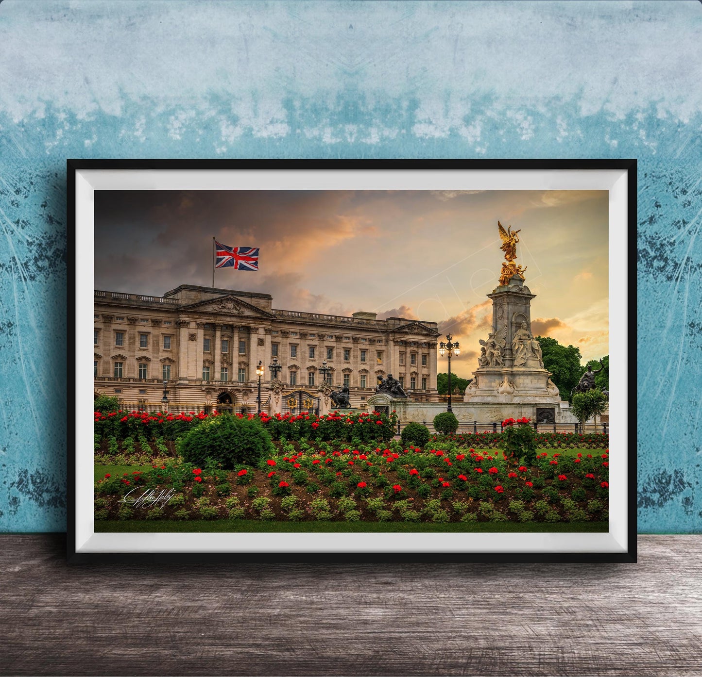 A framed photograph of the Palace of Westminster in London, England, with the British flag flying above the building and a statue in the foreground.