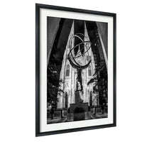A black and white photograph of a large cathedral with a statue in the foreground, framed in a black frame.