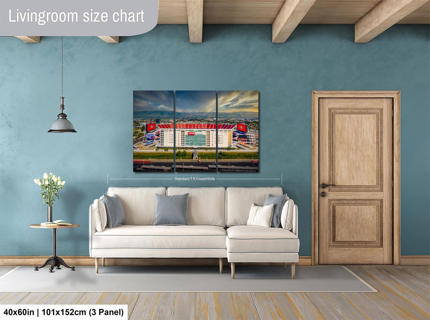 The image is a living room with a large white sofa, a wooden door, and a painting of a stadium on the wall.