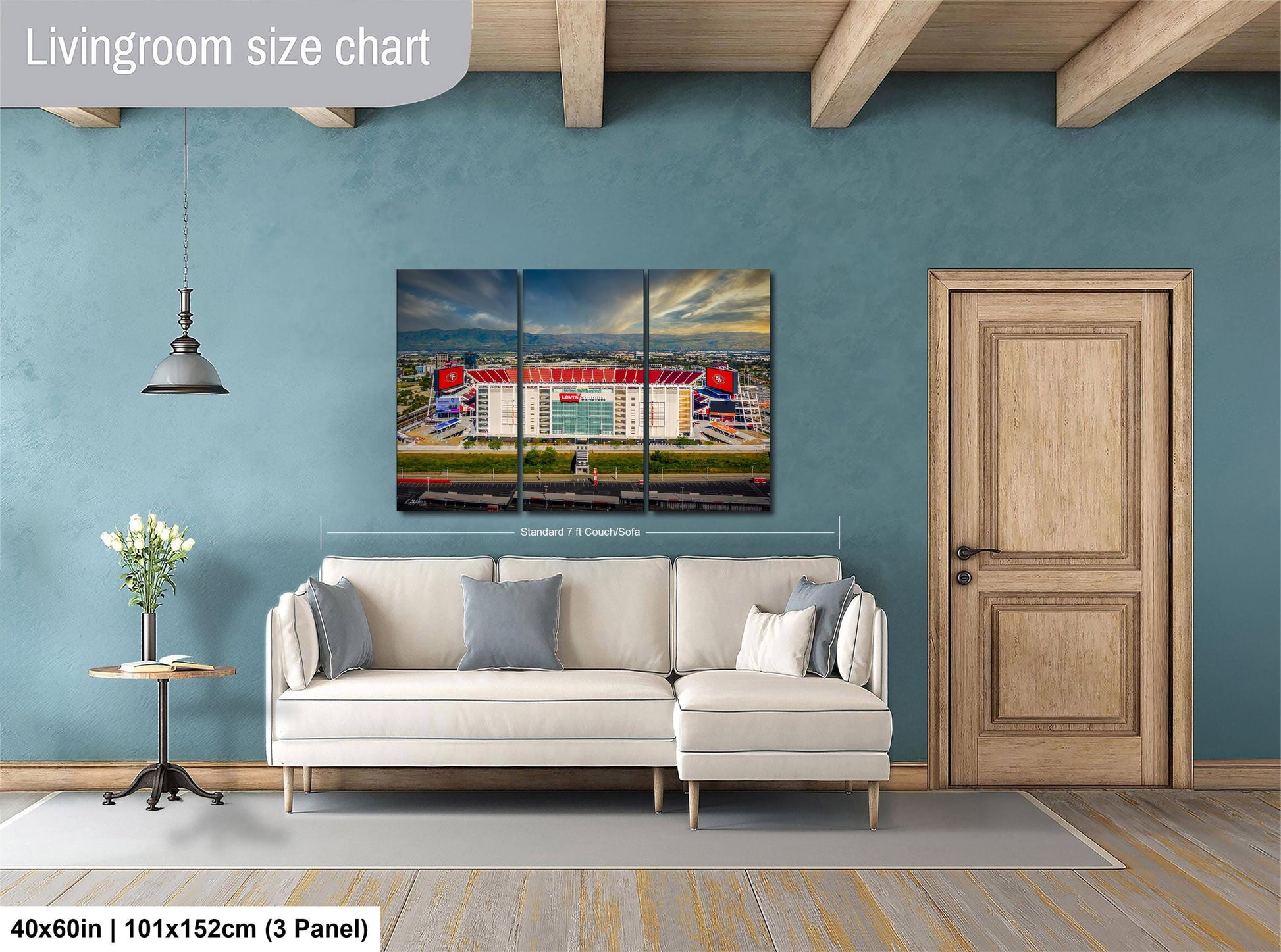 The image is a living room with a large white sofa, a wooden door, and a painting of a stadium on the wall.