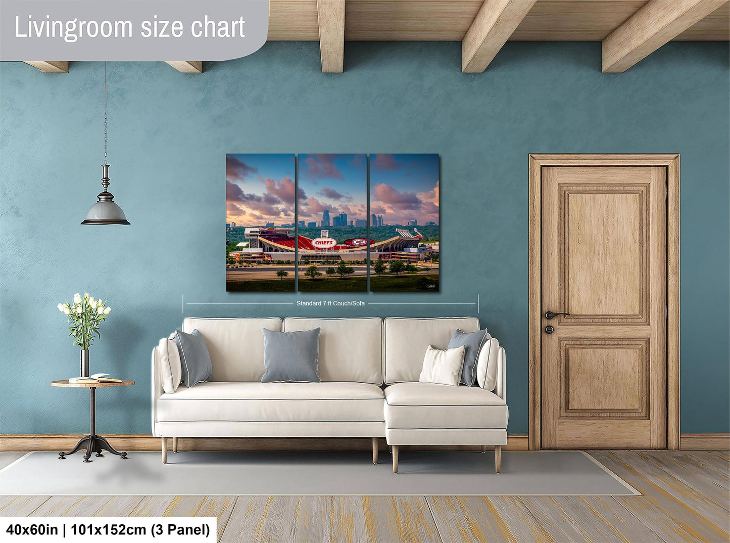 The image is a living room with a large white sofa, a wooden door, and a painting of a stadium on the wall.