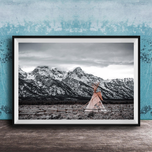 A framed photograph of a teepee in a snowy mountain landscape, with a blue wall in the background.