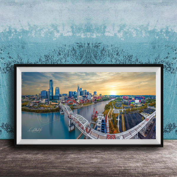 The image is a framed aerial view of a city skyline, featuring a bridge and a river.