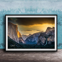 The image is a framed photograph of a breathtaking mountainous landscape at sunset, with dramatic clouds and a waterfall in the foreground.