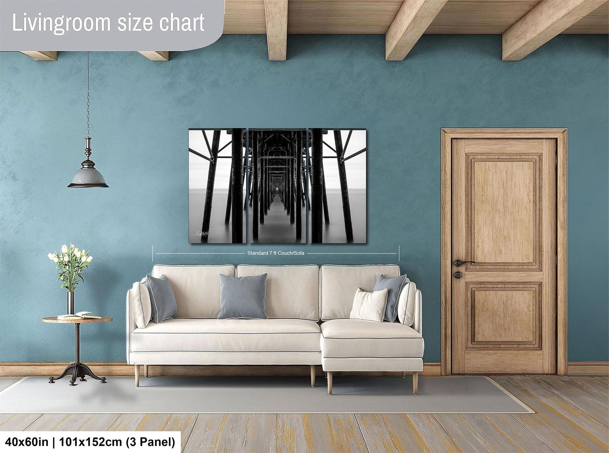 a living room with a white sofa, a wooden door, and a large black and white photograph of a bridge hanging on the wall.