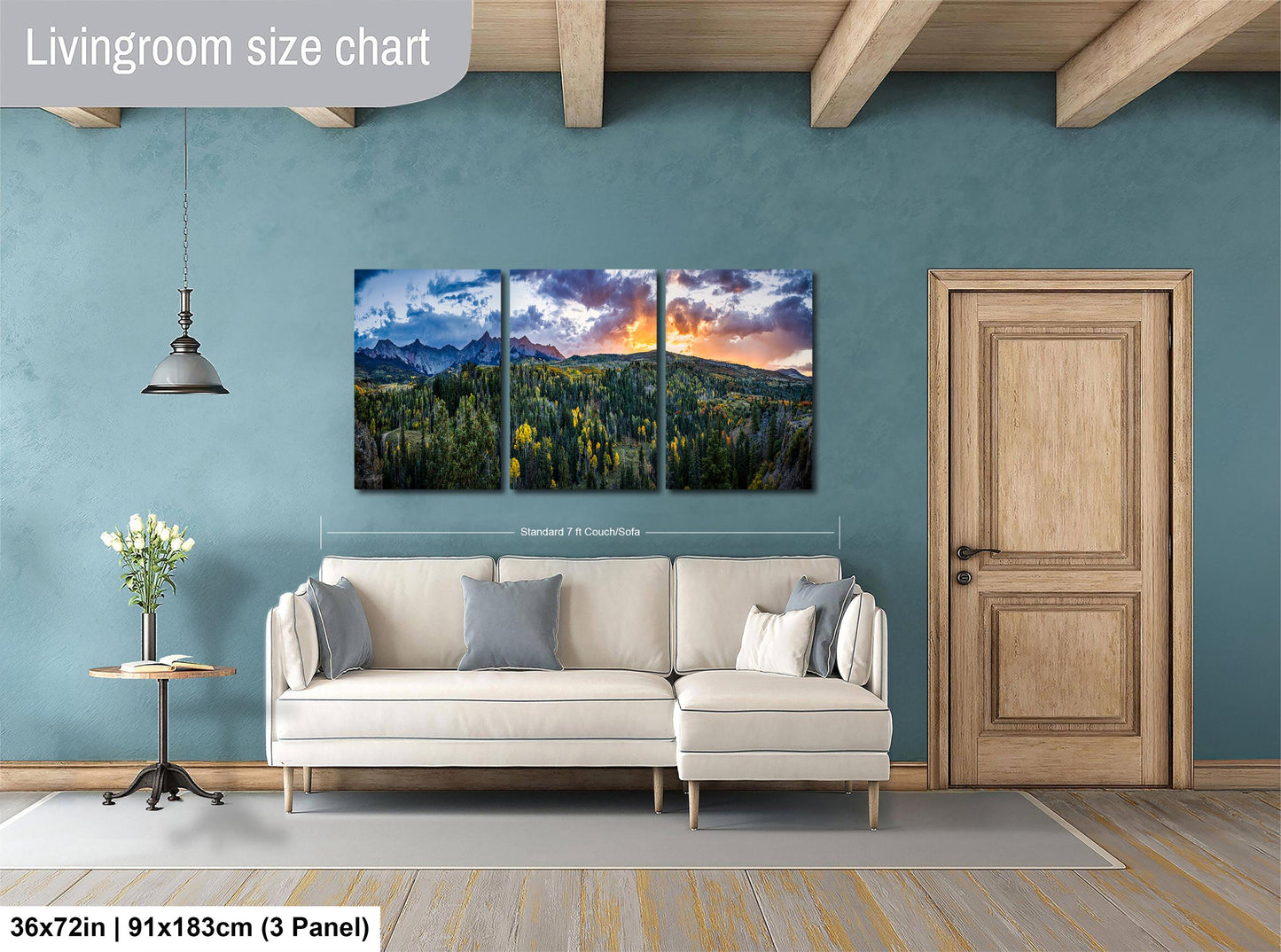The image is a living room with a large, three-panel landscape painting hanging on the wall. The painting depicts a scenic mountain landscape with a colorful sky. The room has a white sofa and a wooden door, creating a cozy and inviting atmosphere.