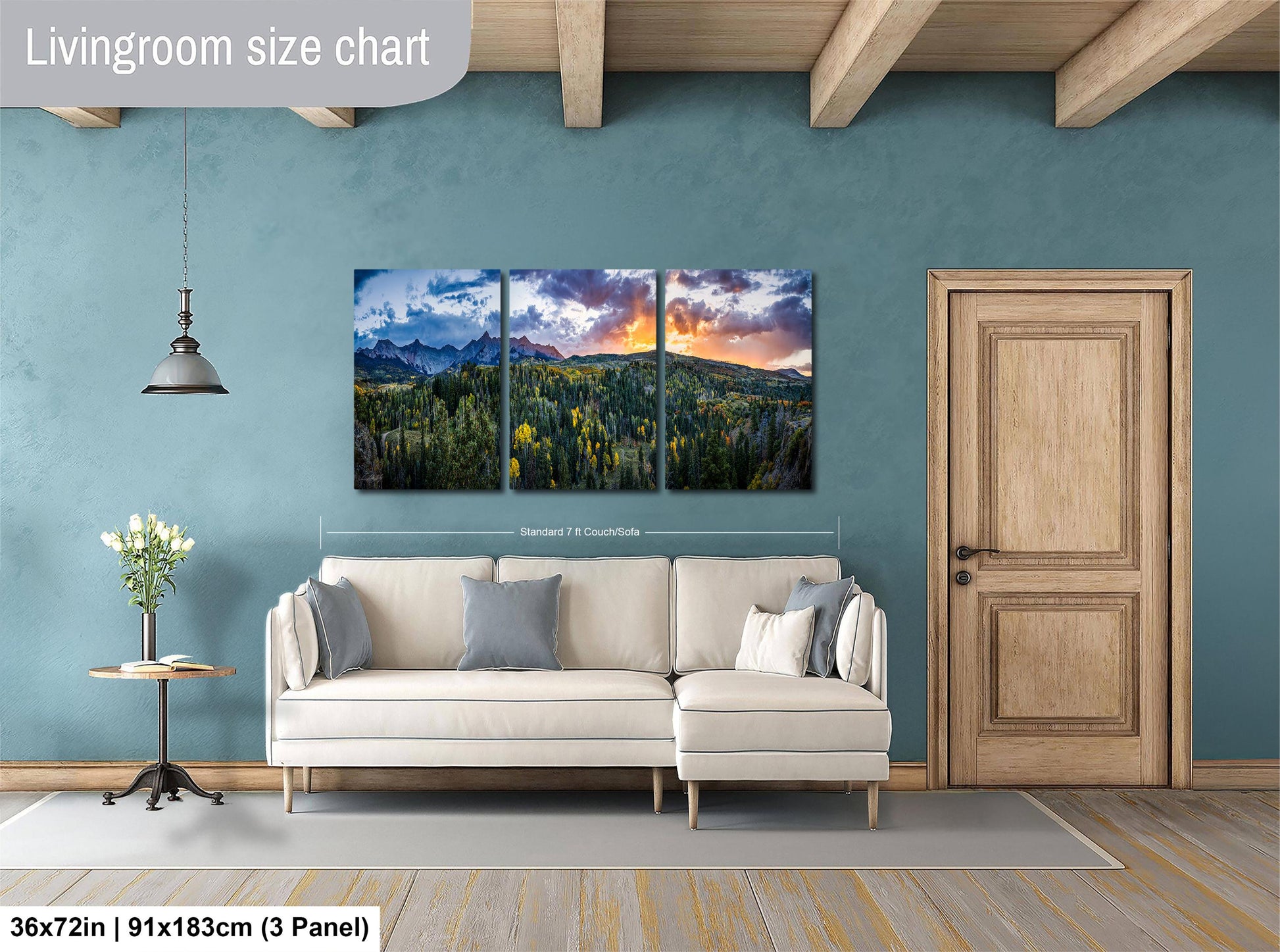 The image is a living room with a large, three-panel landscape painting hanging on the wall. The painting depicts a scenic mountain landscape with a colorful sky. The room has a white sofa and a wooden door, creating a cozy and inviting atmosphere.