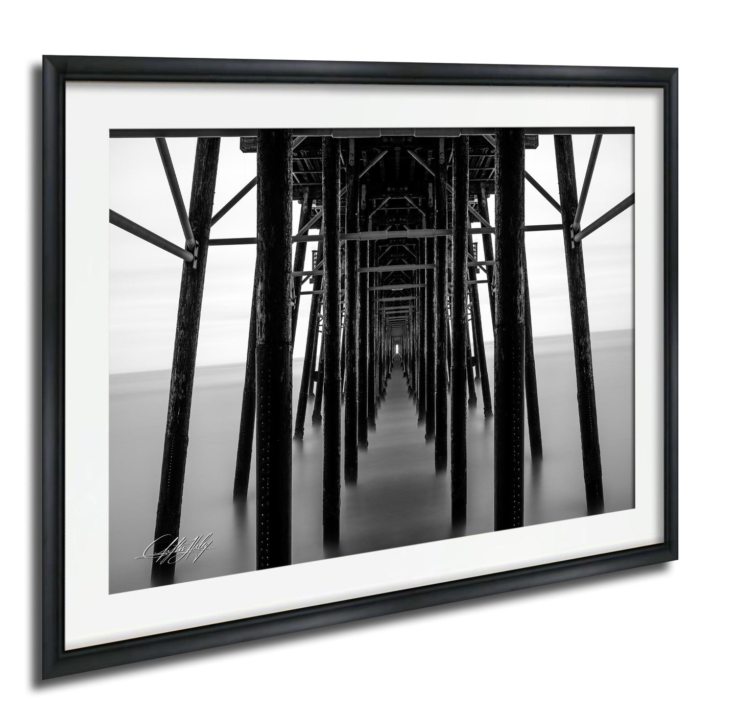 A black and white photograph of a long pier with numerous wooden columns extending into the distance.