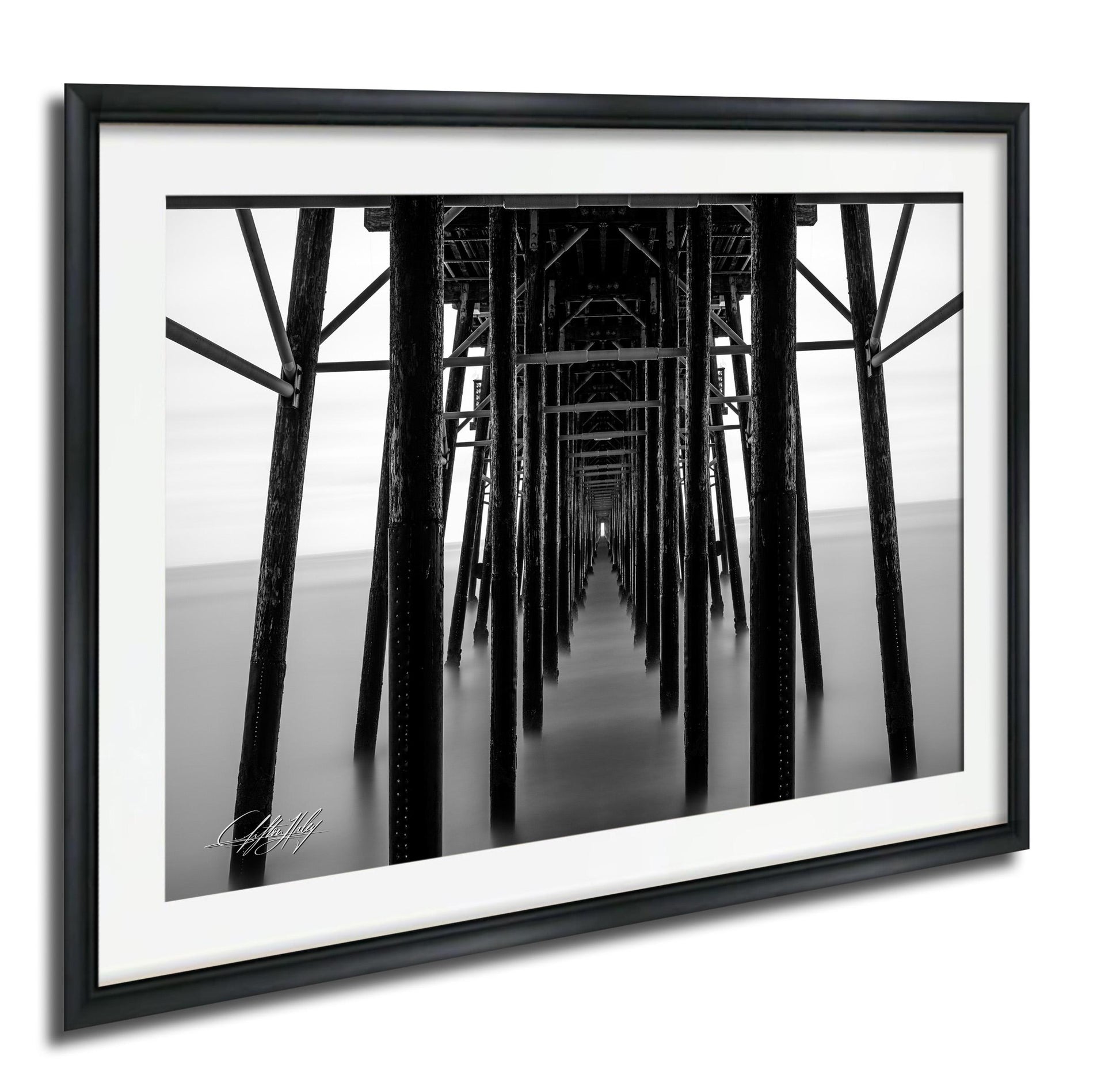 A black and white photograph of a long pier with numerous wooden columns extending into the distance.