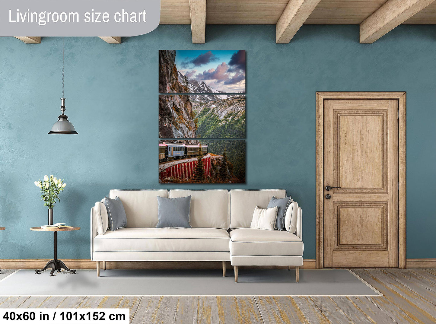 The image is a living room with a large white sofa, a wooden door, and a painting of a mountain landscape hanging on the wall.