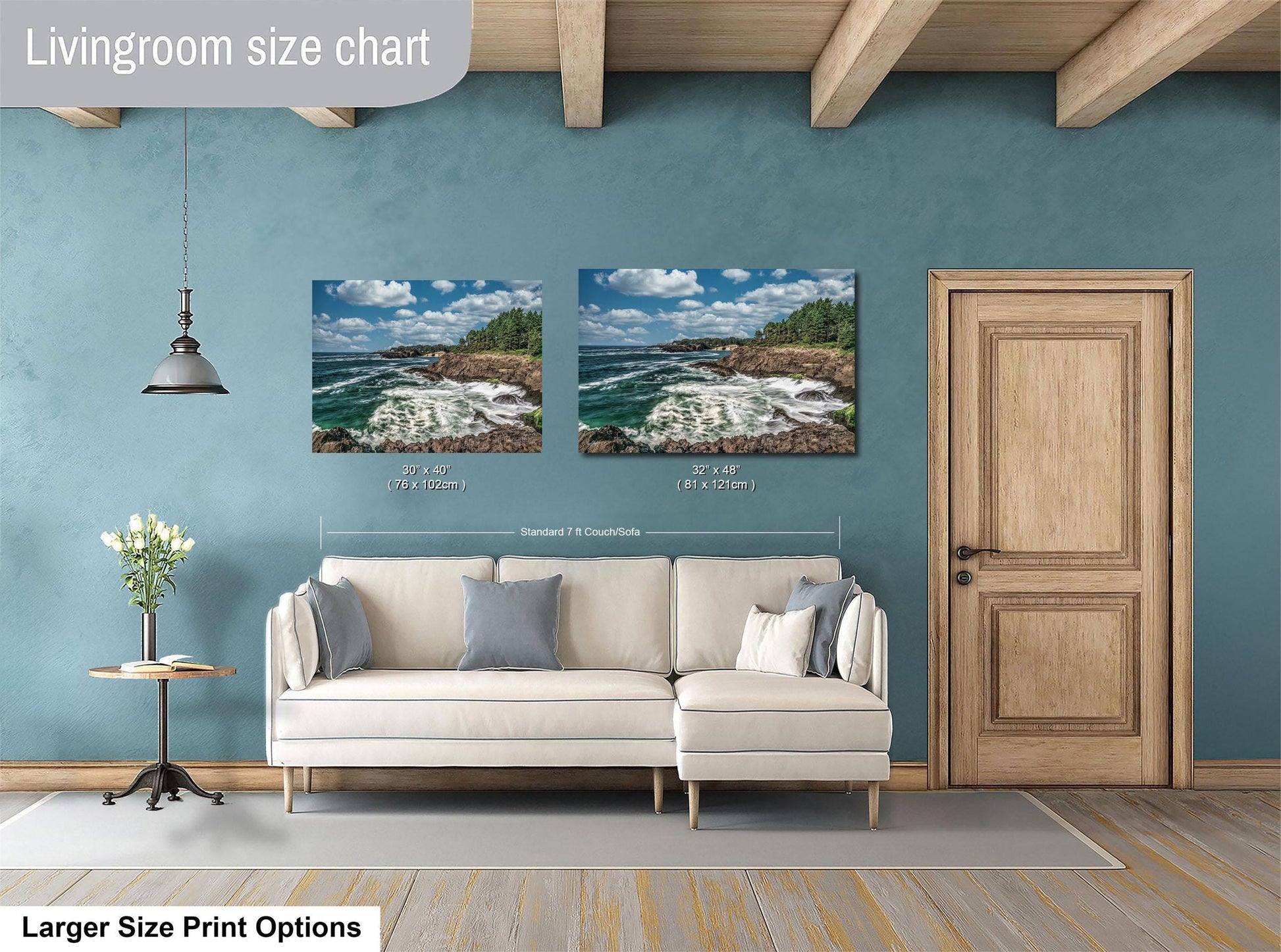 a living room with a white sofa and a wooden door. Above the sofa, there are two framed pictures of a coastal landscape, depicting a rocky shoreline with crashing waves. The living room has a blue wall and a wooden ceiling, creating a cozy and inviting atmosphere.