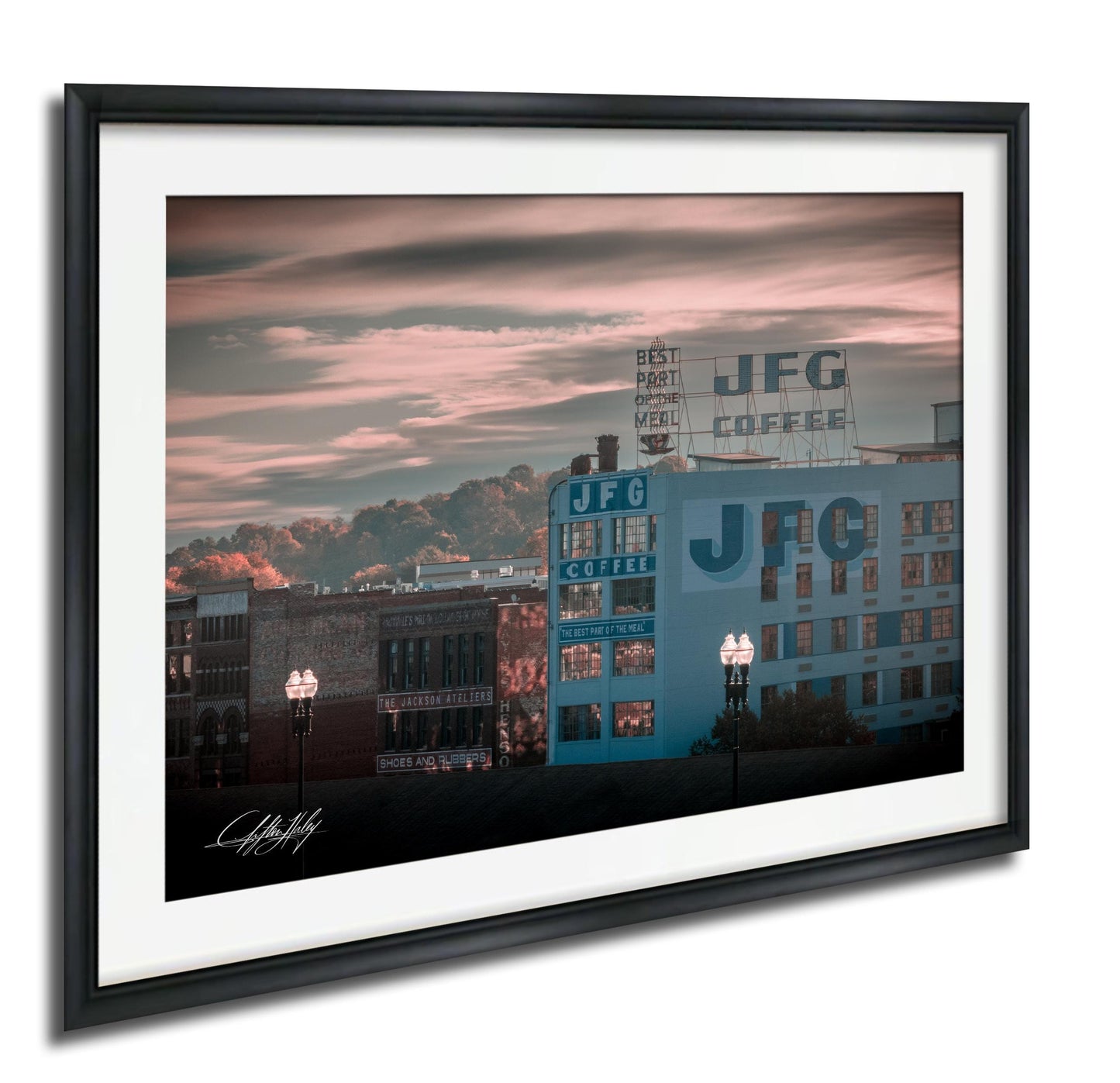 A framed photograph depicting a cityscape with a large J.F.G. Coffee sign on a building, set against a colorful sky with clouds.