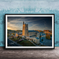 A framed photograph of a large, ornate building with a tower, likely a church, set against a backdrop of a city skyline at sunset.