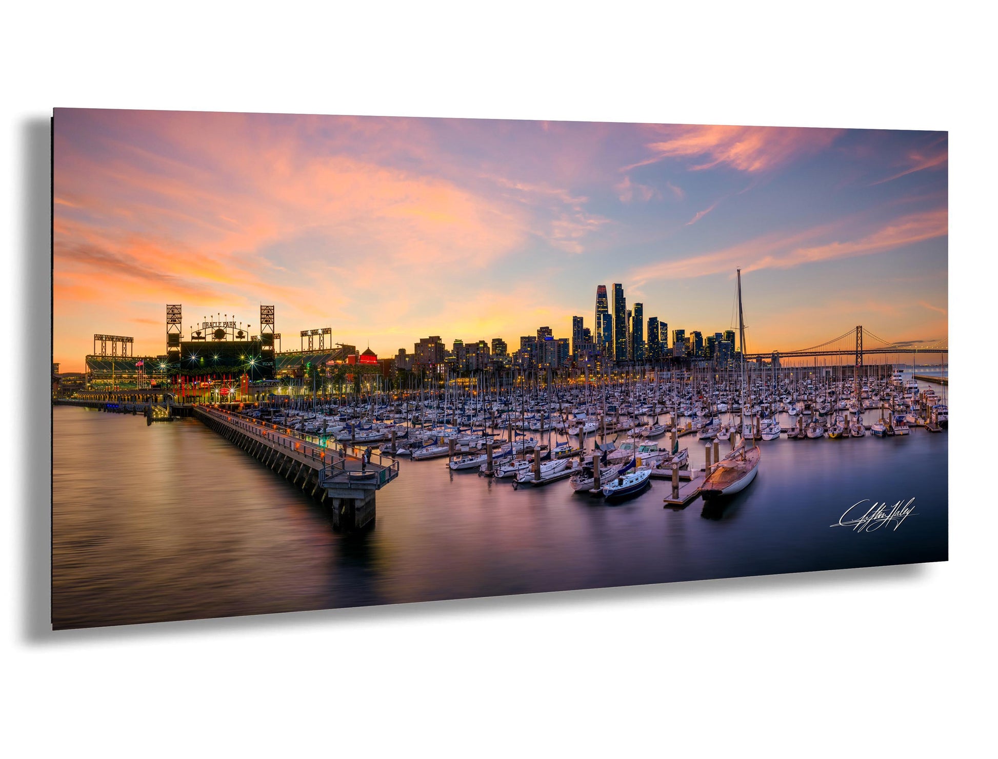 A panoramic view of a city skyline at sunset, with a marina filled with boats in the foreground.