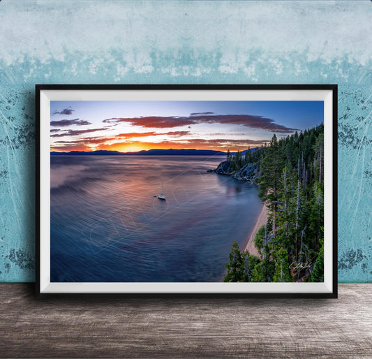 A framed photograph depicting a serene landscape with a calm lake, a boat on the water, and a forested shoreline in the background.