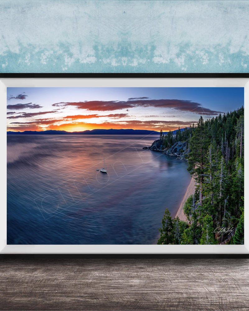 A framed photograph depicting a serene landscape with a calm lake, a boat on the water, and a forested shoreline in the background.