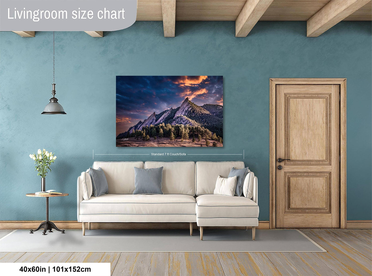 a living room with a large wall painting of a mountain landscape hanging above a white sofa.