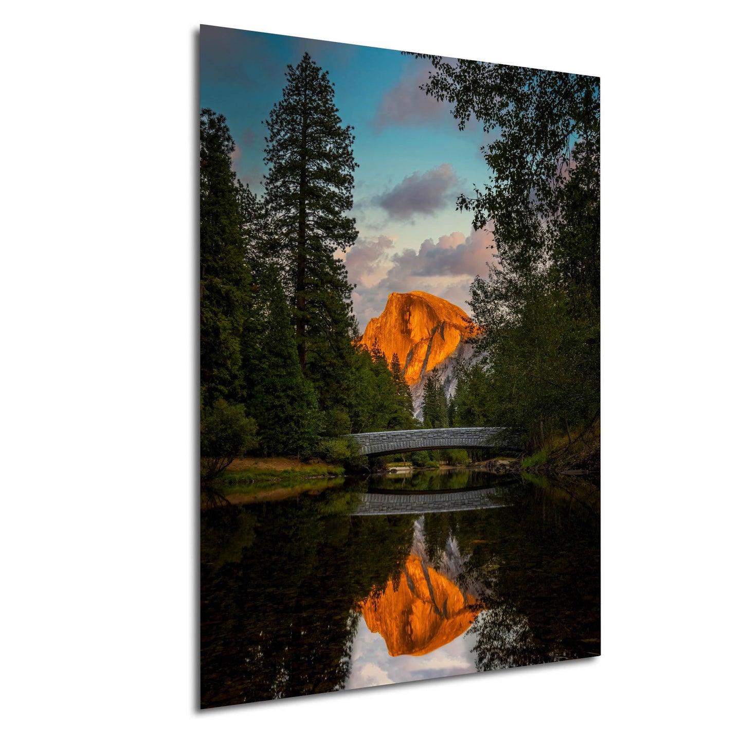 a serene landscape with a bridge spanning a calm river, surrounded by lush greenery and a majestic mountain in the background, with its reflection mirrored in the still waters below.