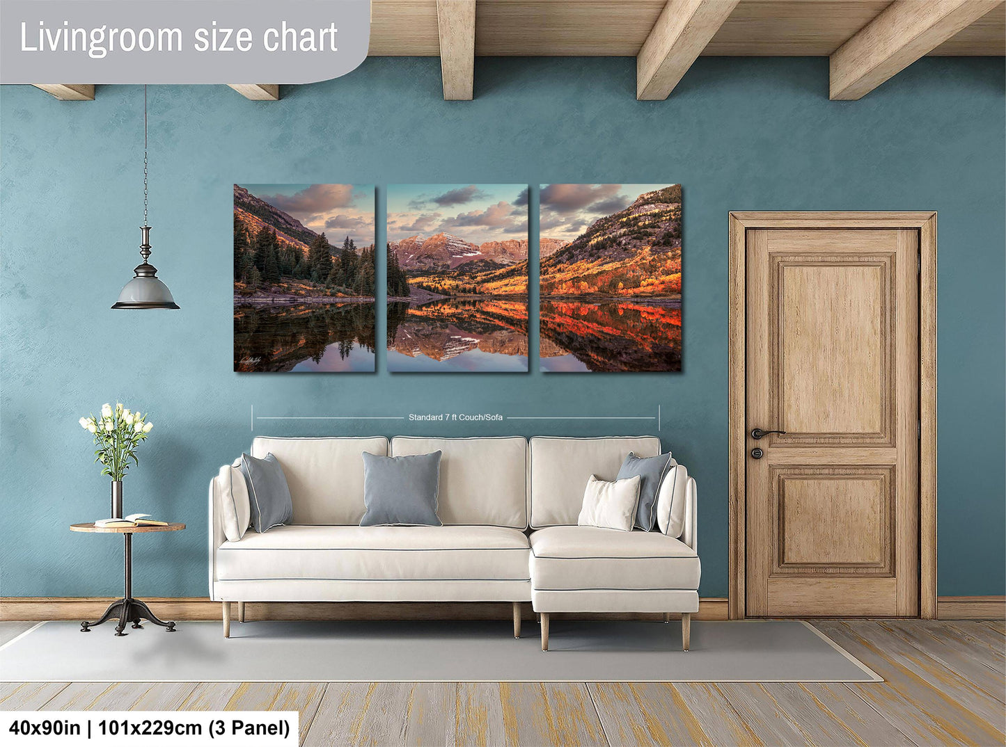 The image is a living room with a large, three-panel landscape painting hanging on the wall. The painting depicts a scenic mountain landscape with a lake and trees. The room has a white sofa and a wooden door, creating a cozy and inviting atmosphere.