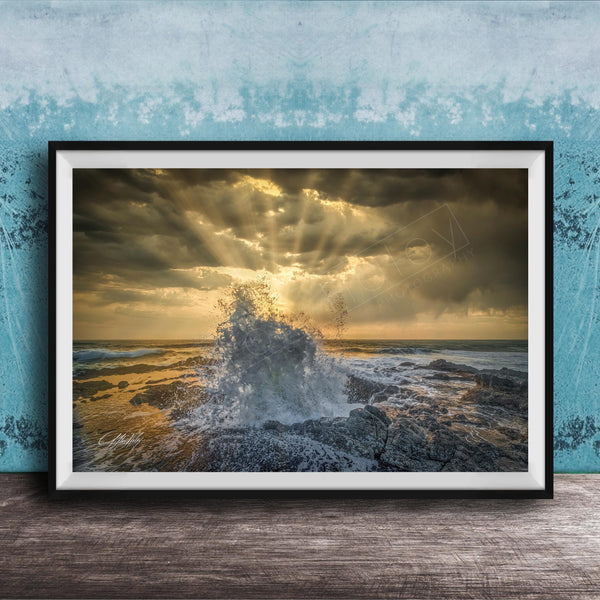 The image is a framed photograph of a dramatic ocean scene, with crashing waves and a dramatic sky filled with clouds and sunbeams.