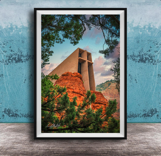 A framed photograph of a large, modern church with a distinctive cross-shaped roof, set against a backdrop of red rock formations and lush greenery.