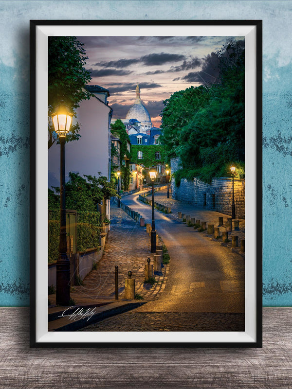 a picturesque street scene in Paris, France, with a cobblestone road lined with trees and lampposts, leading towards a large domed building at the end of the street.