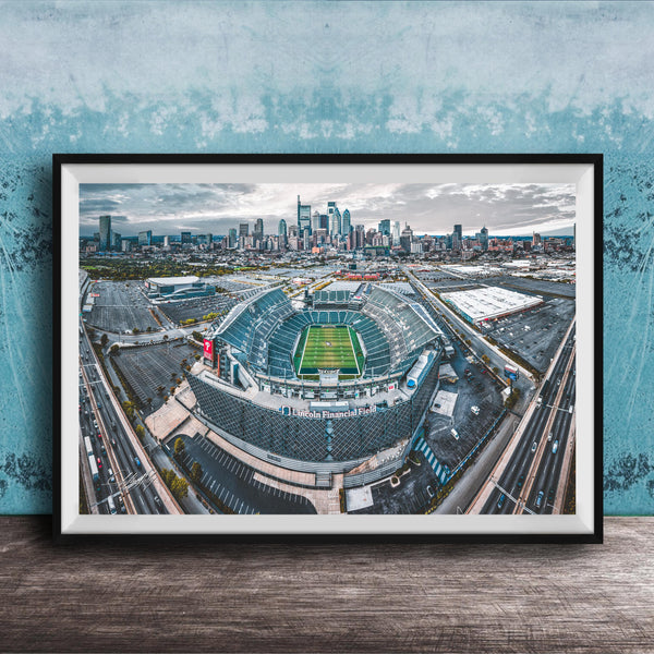 An aerial view of a large sports stadium surrounded by a city skyline, with the stadium's field and surrounding parking lots visible.