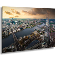 The image is an aerial view of a large city, showcasing a mix of high-rise buildings, roads, and a river or bay. The sky is filled with clouds, creating a dramatic backdrop for the cityscape. The city appears to be a bustling urban environment with a blend of architectural styles and structures.