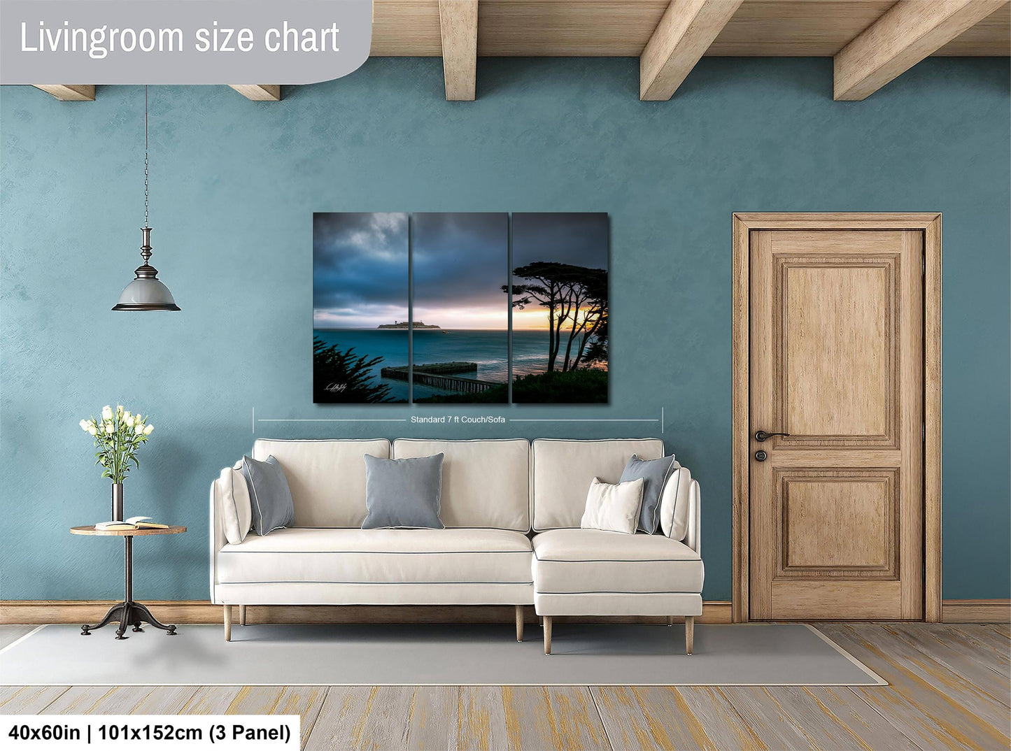 The image is a living room with a large white sofa, a wooden door, and a painting of a seascape hanging on the wall.