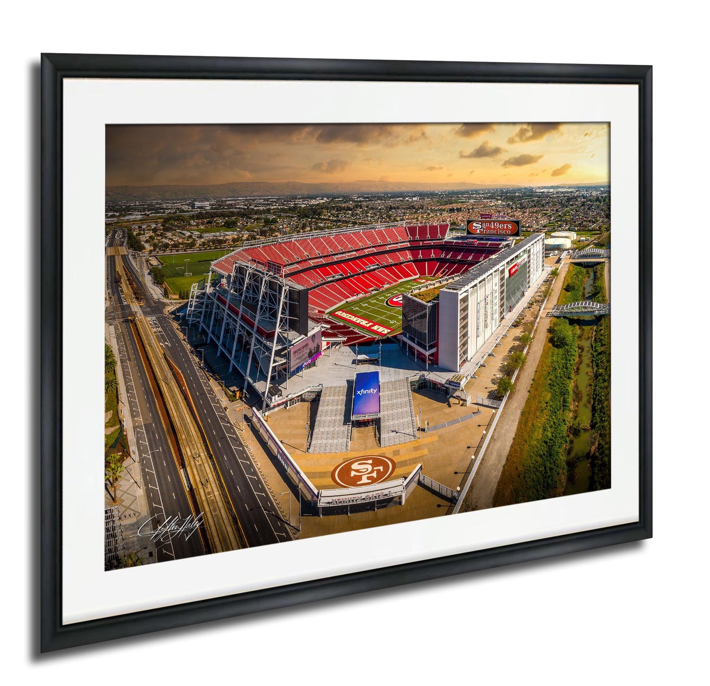 An aerial view of a large sports stadium with a red roof and white walls, surrounded by a cityscape.