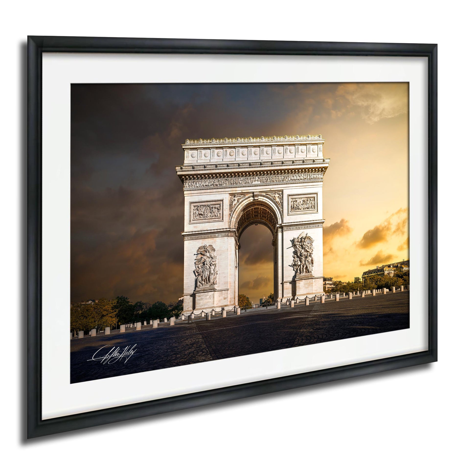 the Arc de Triomphe, a famous monument located in Paris, France. The photograph is framed and displayed on a wall, showcasing the iconic structure against a dramatic sky.